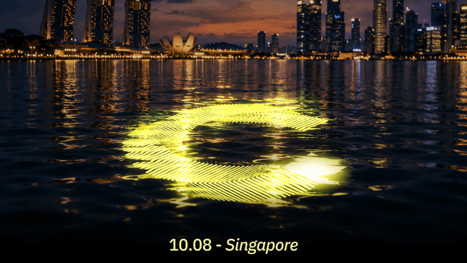 A nighttime view of the Singapore skyline with a glowing, stylized '10.08' (August 10) reflected in the water, with the date and location labeled at the bottom.