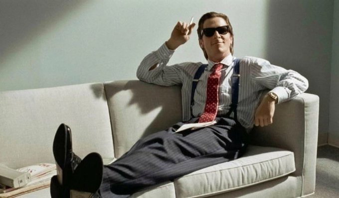 A confident man in sunglasses, suspenders, and a red tie lounges on a white couch while holding up a cigarette, projecting an air of financial savvy that mirrors the post's message about disciplined crypto trading strategies.