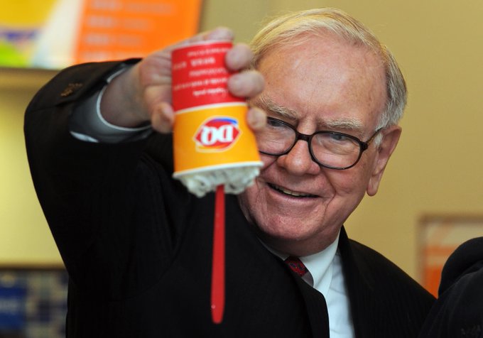 A distinguished older man with glasses holds up a Dairy Queen cup with the iconic "DQ" logo and orange coloring, featuring a red stirrer, while smiling at the camera. The image juxtaposes the post's discussion of options trading volatility and financial strategy with a lighthearted, everyday moment, perhaps symbolizing treating oneself after market moves.