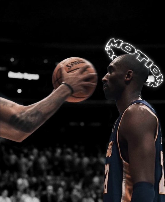A basketball player in a blue jersey faces a hand holding a Spalding basketball, with a 'MOTION' neon sign visible in the dark arena background.