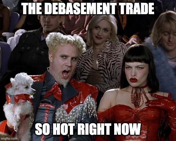 The classic 'So Hot Right Now' Zoolander meme featuring Mugatu and a woman in red, with overlay text reading 'THE DEBASEMENT TRADE SO HOT RIGHT NOW'.