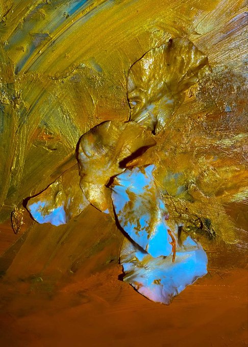 A close-up abstract painting featuring thick, impasto strokes of gold, yellow, orange, and bright blue paint.