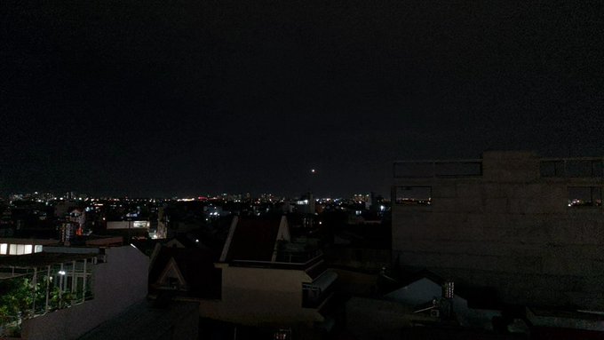 A quiet nighttime cityscape with scattered lights glowing across distant buildings under a dark sky. The still, steady lights mirror the post's message about consistency compounding over time.