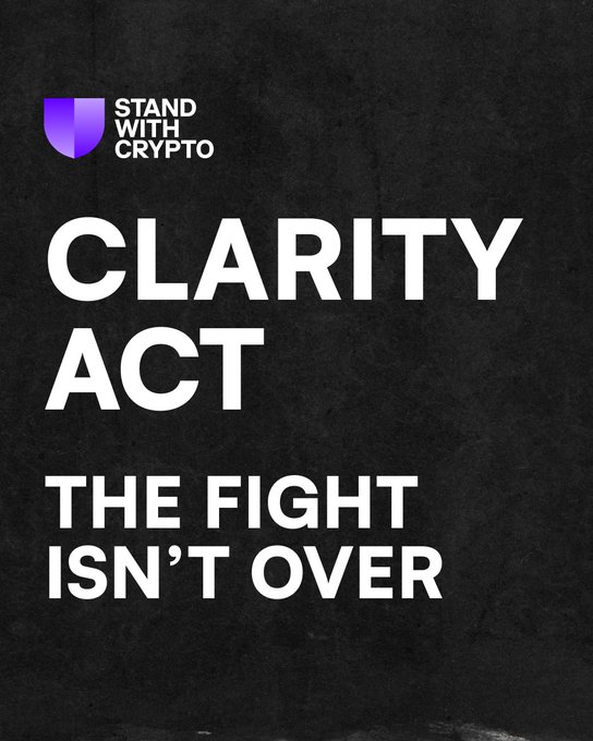 A black graphic from Stand With Crypto featuring bold white text reading "CLARITY ACT — THE FIGHT ISN'T OVER," with the organization's purple shield logo in the top left corner. The image reinforces the post's message that despite the CLARITY Act missing a pre-recess vote, advocacy efforts must continue until crypto legislation is secured.