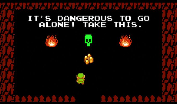 A retro video game scene displays the famous line "IT'S DANGEROUS TO GO ALONE! TAKE THIS." in white pixel text, with a green character below standing before a sword, flanked by two torches. The screen is bordered by a decorative red pixelated frame.