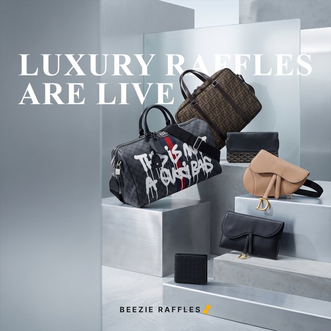 A luxury advertisement for "BEEZIE RAFFLES" announcing "LUXURY RAFFLES ARE LIVE", displaying several designer handbags and accessories arranged on metallic pedestals, including Dior-branded bags with graffiti text reading "This is not a Dior bag".
