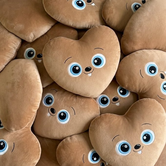 A collection of plush potato-shaped pillows with cute cartoon faces (blue eyes, small smiles, and a single tooth) piled together.