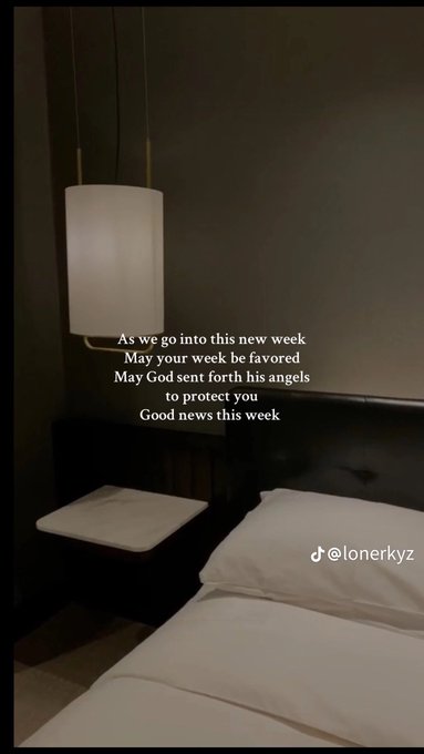 A dimly lit bedroom scene features a hanging white pendant lamp above a neatly made bed, overlaid with an inspirational message: "As we go into this new week / May your week be favored / May God sent forth his angels to protect you / Good news this week." The post by @lonerkyz, directed at $ANSEM holders, pairs the hopeful "good news" blessing with an optimistic outlook on upcoming developments for the ticker.