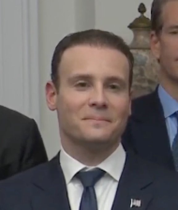 A photograph of French President Emmanuel Macron in a dark suit and tie, appearing with a tight-lipped expression during what looks like an official meeting.