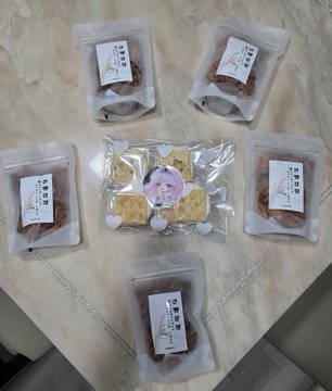 Several small, clear plastic packages containing what appears to be homemade snacks or baked goods, arranged on a marble surface.