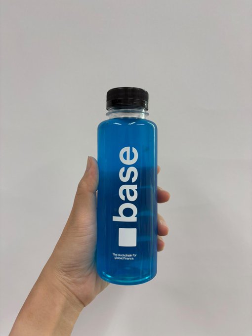 A hand holding a bottle of blue liquid labeled 'base' with the tagline 'The blockchain for global finance.'