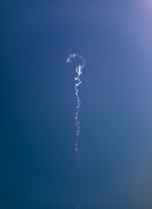 A minimalist composition showing a single, wispy curling line of smoke or vapor rising against a deep blue gradient background.