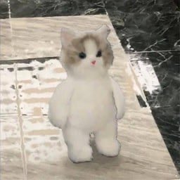 A small, fluffy white and beige plush cat toy with pink accents stands upright on a marble-like tiled floor, appearing as the subject "MIU" referenced in the post about Solana posting pictures of @fluffyonchain.