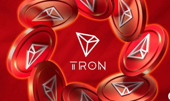 A promotional graphic for TRON cryptocurrency featuring the TRON logo (TRX) in the center surrounded by multiple red metallic 3D coin representations of the same logo.