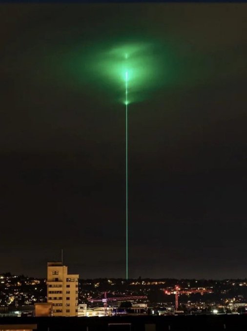 A brilliant green laser beam shoots skyward into a glowing cloud above a city skyline at night. The dramatic illumination evokes anticipation, fitting the "Ready for this?" caption as if signaling a major event or spectacle about to unfold.