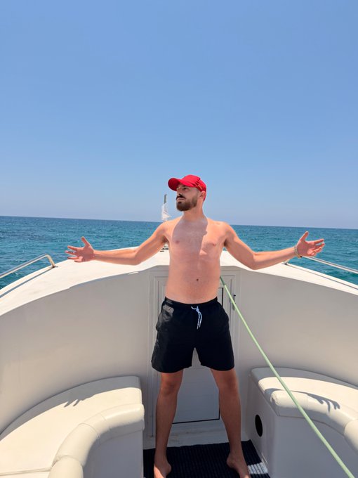 A shirtless man wearing a red cap stands on a yacht with arms outstretched, facing the open sea as if embracing a triumphant moment. The image of someone sailing into vast waters symbolizes embarking on a bold, prosperous journey—fitting the post's bullish declaration about an unprecedented crypto rally.