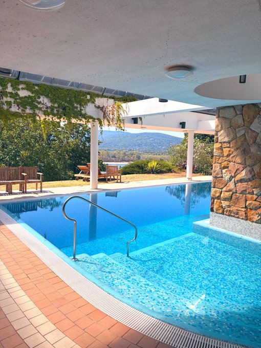 An indoor swimming pool with lounge chairs, stone walls, and a scenic mountain view in the background complements the post's vibe of a relaxed Sunday hangout with friends ("Sunday maxxing with my homies") — no text or numbers are visible in the image itself.