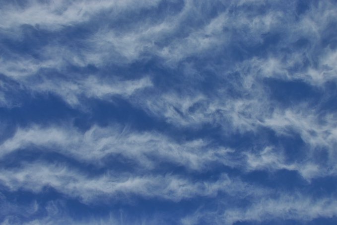 Wispy cirrus clouds scattered across a bright blue sky.