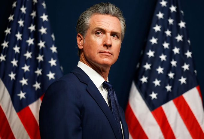A man in a navy suit and tie stands with American flags in the background. The post suggests this relates to a political endorsement, framing him as stepping aside to pave the way for Kamala Harris to lead.