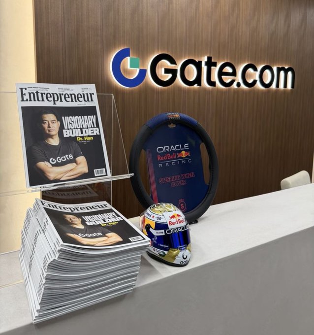 A display at GGate.com featuring Entrepreneur magazine covers with Dr. Han titled 'Visionary Builder,' alongside Oracle Red Bull Racing merchandise including a steering wheel and a helmet.