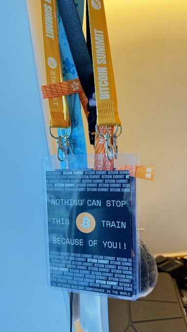 A plastic event badge on lanyards that read 'BITCOIN SUMMIT', with the message 'NOTHING CAN STOP THIS TRAIN BECAUSE OF YOU!!' and references to 'BTC' and 'STOCKS'.