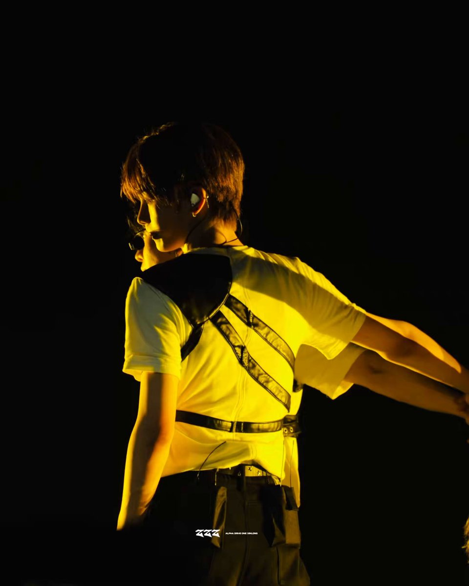 그리고, there is a boy wearing a backless shirt at an outdoor event with a bright stage light. The caption reads: "260614 Chains #xinllong #ALD1 #ALD1". This description indicates that the image was taken during an outdoor concert or festival where people are gathered in front of a brightly lit stage area, enjoying the performance and likely being influenced by the music's message or energy.