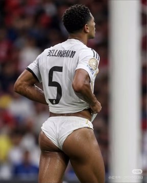 A soccer player wearing a white jersey with 'BELLINGHAM' and the number 5 on the back stands on the field, appearing to adjust his shorts.