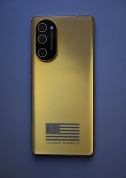 A gold-colored smartphone with a black camera module, featuring an American flag graphic and the text 'TRUMP MOBILE' on the back.