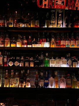 The image features a large shelf filled with various bottles of alcohol, including wine and liquor. The bottles are arranged in an organized manner, showcasing their contents for sale or display purposes. The background appears to be a dark room, which further emphasizes the prominence of the alcohol bottles on the shelf. The post accompanying the image provides information about the different types of alcohol available, possibly indicating that this is a store selling liquor and wine products.
