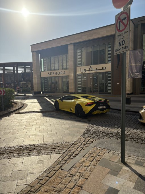 A bright yellow Lamborghini Huracán is parked in front of a Sephora store, with the English and Arabic "SEPHORA" signage clearly visible, and a "NO RIGHT TURN" sign nearby—fitting the post's "GM (get money)" caption as a flashy display of wealth and luxury.
