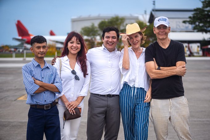 Five people pose together on an airport tarmac, smiling in front of a red and white airplane, celebrating the success of El Salvador's Bitcoin adoption—the world's first nation to embrace Bitcoin as legal tender.