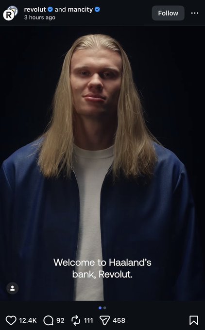 The image features a man with long blonde hair wearing a blue jacket, standing against a black background. The caption of the image reads "Welcome to Haaland's bank Revolut", indicating that the photo was taken at the bank. The man is smiling and looking directly at the camera, creating an engaging and friendly atmosphere for the post.