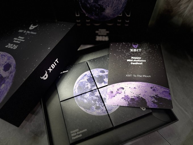 Black gift boxes and packaging with purple moon graphics and text including "XBIT", "Happy Mid-Autumn Festival", "To The Moon", and "2026".