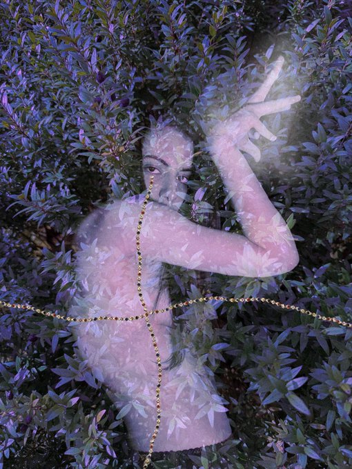 An ethereal double-exposure photograph blending a person's profile with purple and green foliage, creating a dreamlike, layered effect.
