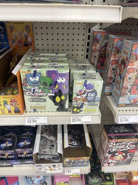 A store shelf displaying Pokémon Trading Card Game products, including tins priced at $59.99, alongside other trading card game merchandise.
