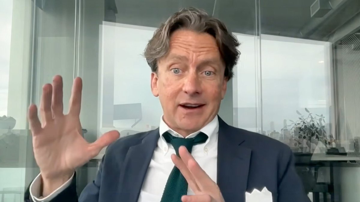 A man in a dark suit and green tie, identified as Charley Cooper of Ava Labs, speaks directly to the camera with an expressive gesture, raised hand, against a bright, modern office backdrop. The image visually reinforces the post's message about blockchain enabling 24/7 global markets, positioning him as an expert sharing insights on the future of always-on financial infrastructure.