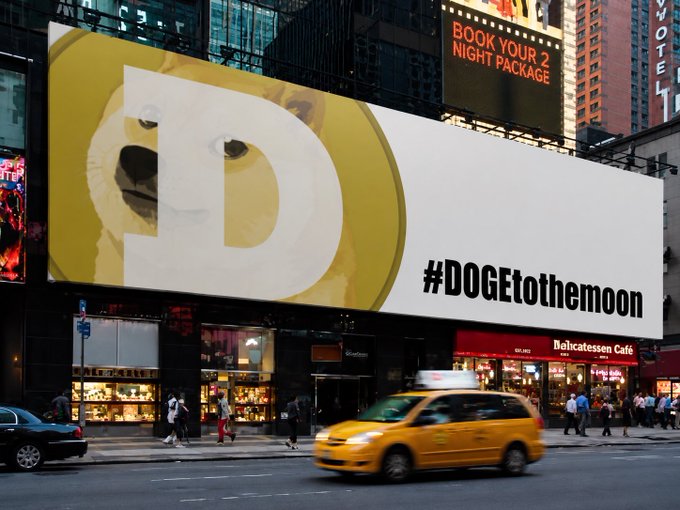 A massive billboard in New York City's Times Square features the Doge meme with the hashtag "#DOGEtothemoon," prominently displayed above street-level shops like "Delicatessen Café" and alongside a yellow taxi passing by. The advertisement captures the viral crypto meme phenomenon, aligning with the 2021 Dogecoin rally that fueled its meteoric price rise.