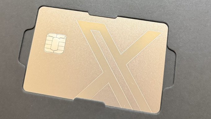 A gold X-branded SIM card or payment card with a visible chip sits in a dark tray, visually symbolizing the rumored launch of X Money, the upcoming financial/payment service from X, in Canada.