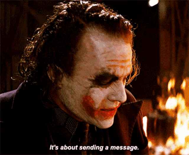 The Joker (with smeared clown makeup and dark eye shadow) looks downward pensively as flames burn behind him, with the subtitle "It's about sending a message." The image mirrors the post's theme — like the Joker orchestrating chaos for attention, the referenced fake Bitcoin ETF tweet sent a shockwave through the market, wiping out months of gains in a single day as a deliberate message to investors.