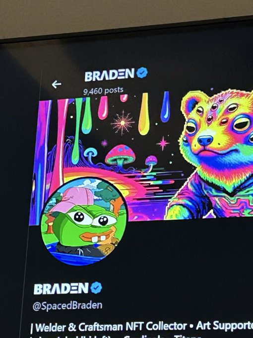 A Twitter/X profile page for "BRADEN" (@SpacedBraden) showing a verified account with 9,460 posts, featuring a vibrant psychedelic banner with a rainbow bear and dripping neon colors, alongside a cartoon frog avatar.