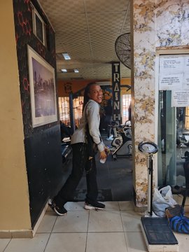 A man stands in a gym doorway with 'TRAIN' signage visible on the wall behind him.