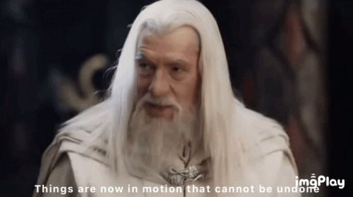 The image features a man with white hair, dressed as a wizard or a gnome, standing against a dark background. He appears to be looking directly at the camera, giving off an air of mystery and intrigue. The text "things are now in motion that cannot be undone" is written below him, which could be interpreted as a quote from a famous speech by Martin Luther King Jr., emphasizing the idea that once something happens, it's difficult or impossible to change it completely. This message seems fitting for the image of the man with white hair and long beard, who may represent wisdom or experience but cannot alter his past actions.