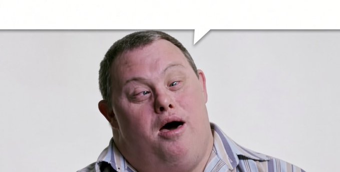 A close-up of a man with short hair and a striped shirt has an animated speech bubble above his head, suggesting he is speaking.