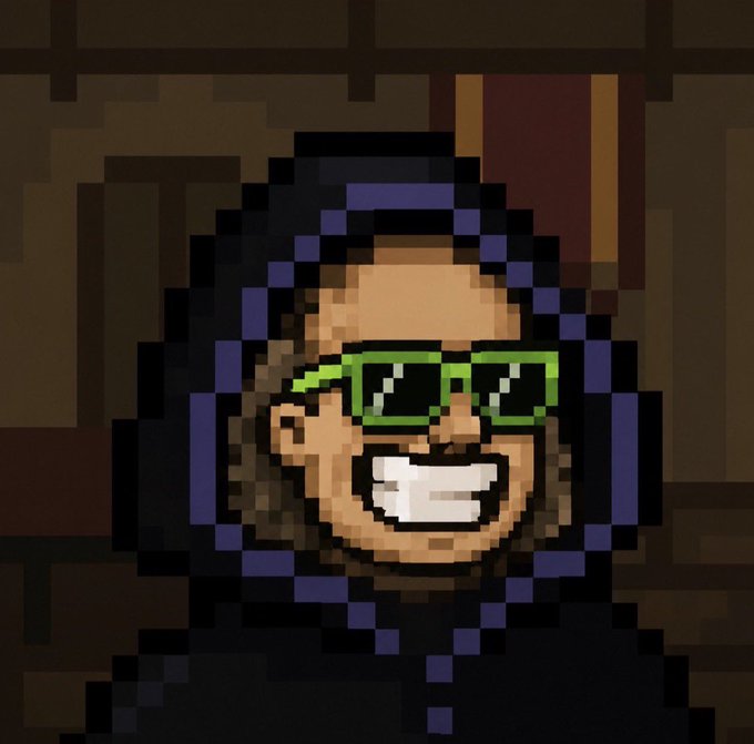 A pixel art portrait of a smiling bearded person wearing bright green glasses and a dark hooded outfit.