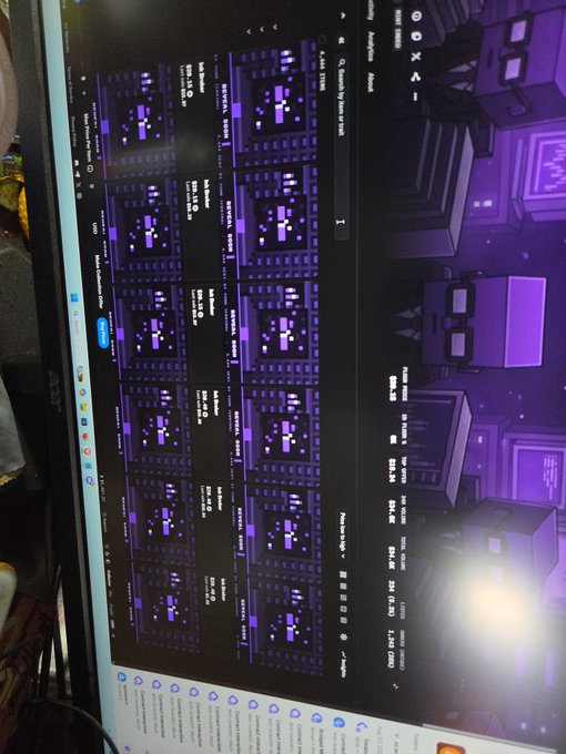 A computer monitor displaying a grid of purple-themed pixel art or game tiles with various icons and small text.