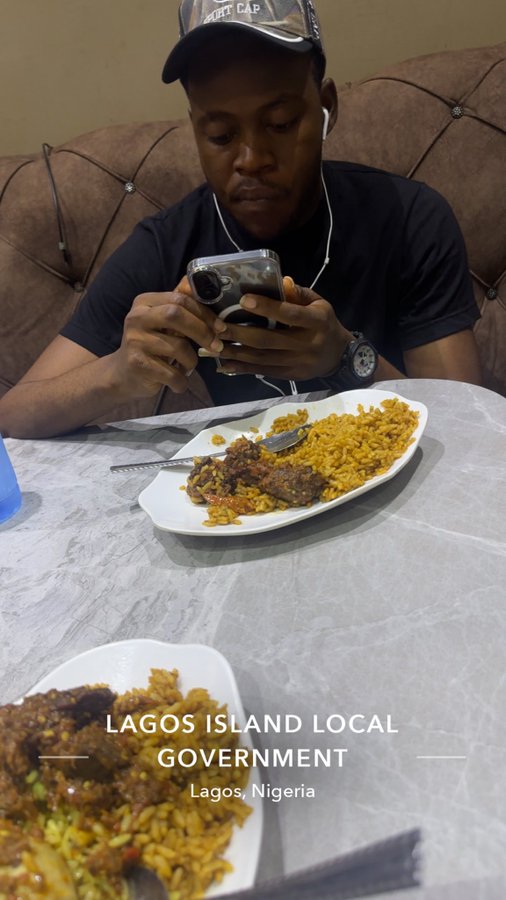 A man wearing a cap and earphones sits at a table eating a plate of yellow rice and stew, with text overlay reading 'LAGOS ISLAND LOCAL GOVERNMENT, Lagos, Nigeria'.