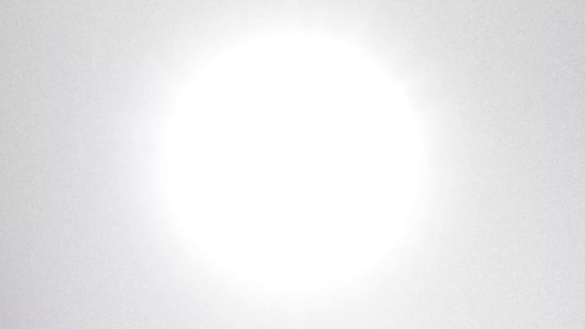 The image features a white circle with an even larger white circle inside it, creating a sense of depth and perspective within the frame. The background appears to be a gradient of grey or brown, which further emphasizes the stark contrast between the two circles. The overall composition suggests that the main focus is on the two white circles and their relationship to one another.