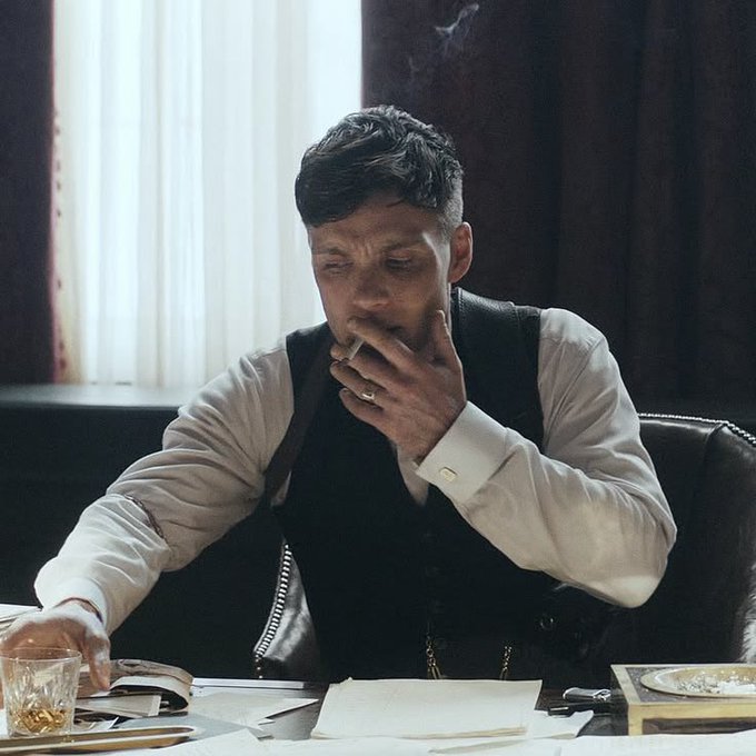 The image features a man sitting at a desk, smoking a cigarette while reading a book or newspaper. The scene takes place near a window, which suggests that he might be indoors during the morning hours. The photo has been captioned with the message "good morning frens daily reminder... don't fade @wolfswapdotapp you can never go wrong with them have a great day!". This message seems to be related to the man's smoking habit and his choice of reading material, as it implies that he is not taking care of himself or his health by engaging in such activities.

The image also includes some objects on the desk, like an open book and a glass, which further emphasize the setting. The presence of these items suggests that this scene might be set in someone's home office or a similar environment where they spend time reading and smoking during their morning routine.
