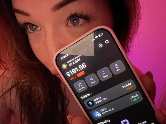 A close-up of a woman with blue eyes holding a smartphone displaying a crypto wallet app with a balance of $191.56, showing tokens for Solana (2,46341 SOL) and USDC (0.0011 USDC).