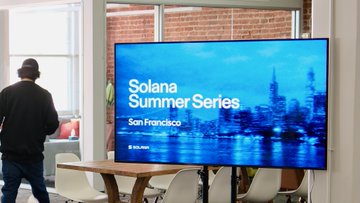 A TV screen displays a "Solana Summer Series - San Francisco" banner, alongside a person wearing a beanie standing near a table. The image reflects the Solana Demo Night event referenced in the post, where the cofounder presented Clawpump's achievements, including $110M in agentic volume and 5,100 SOL distributed to builders.